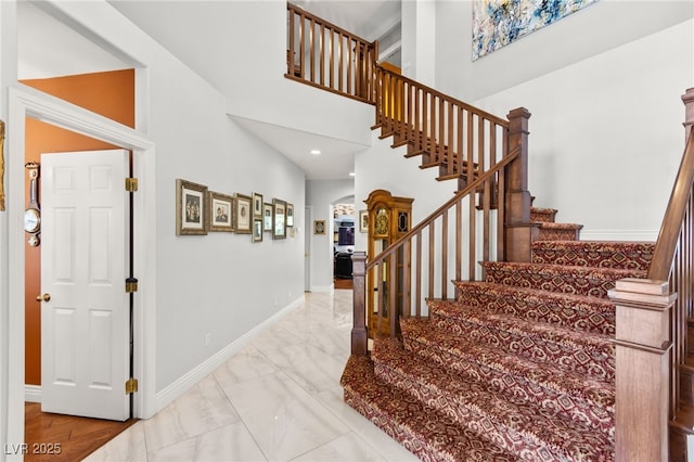 7428 Doe Ave, Las Vegas, NV 89117 - staircase with arched walkways, a towering ceiling, marble look tiles, and recessed lighting