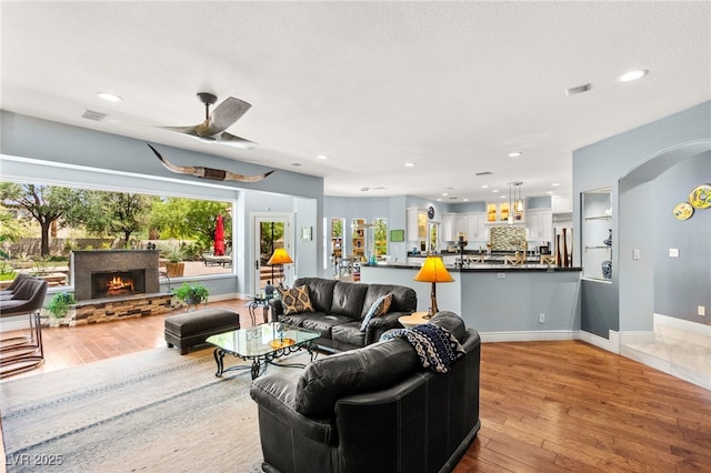 7428 Doe Ave, Las Vegas, NV 89117 - living area featuring light wood-style flooring, arched walkways, ceiling fan, a stone fireplace, and recessed lighting