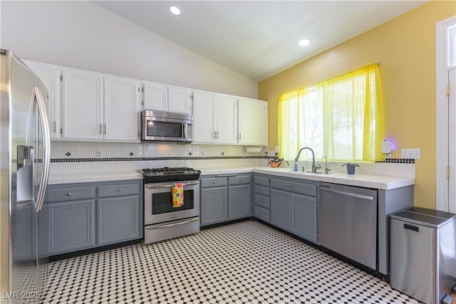 3650 Russian Olive St, North Las Vegas, NV 89032 - kitchen featuring appliances with stainless steel finishes, gray cabinetry, vaulted ceiling, light countertops, and decorative backsplash