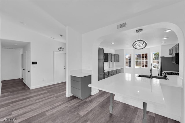 6129 Bedrock Ct, North Las Vegas, NV 89031 - kitchen featuring dark wood-style floors, light countertops, arched walkways, and pendant lighting