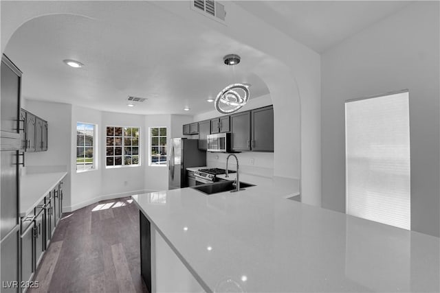 6129 Bedrock Ct, North Las Vegas, NV 89031 - kitchen with arched walkways, appliances with stainless steel finishes, dark wood-style flooring, light countertops, and recessed lighting