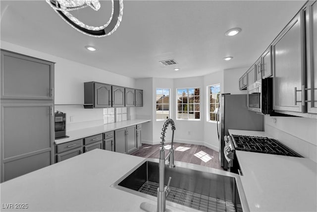 6129 Bedrock Ct, North Las Vegas, NV 89031 - kitchen with gray cabinets, stainless steel appliances, light countertops, recessed lighting, and dark wood-style flooring