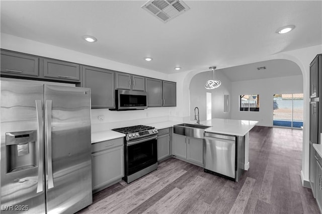 6129 Bedrock Ct, North Las Vegas, NV 89031 - kitchen featuring appliances with stainless steel finishes, arched walkways, gray cabinetry, a peninsula, and light countertops