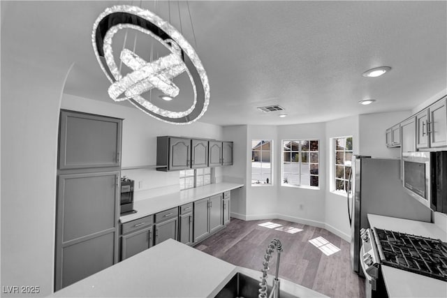 6129 Bedrock Ct, North Las Vegas, NV 89031 - kitchen featuring gray cabinets, stainless steel appliances, dark wood-style flooring, light countertops, and a textured ceiling