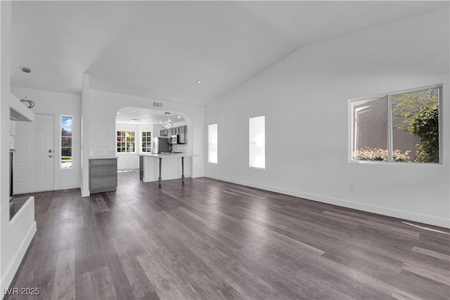 6129 Bedrock Ct, North Las Vegas, NV 89031 - unfurnished living room featuring arched walkways, lofted ceiling, and dark wood-type flooring