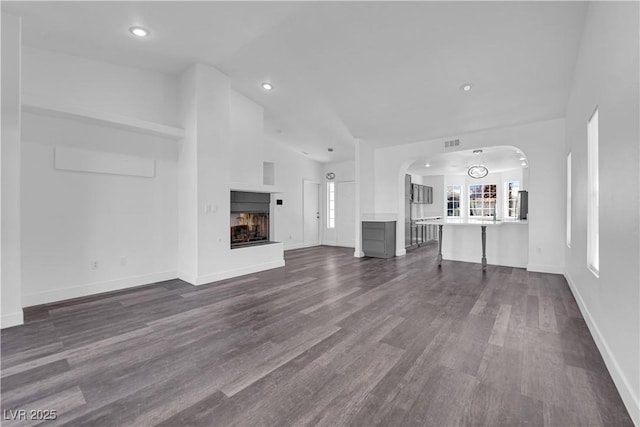 6129 Bedrock Ct, North Las Vegas, NV 89031 - unfurnished living room featuring dark wood-type flooring, a multi sided fireplace, recessed lighting, and arched walkways