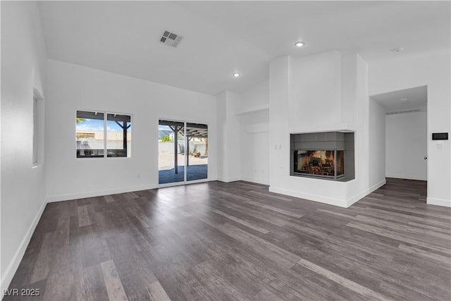 6129 Bedrock Ct, North Las Vegas, NV 89031 - unfurnished living room with a multi sided fireplace, dark wood-type flooring, lofted ceiling, and recessed lighting