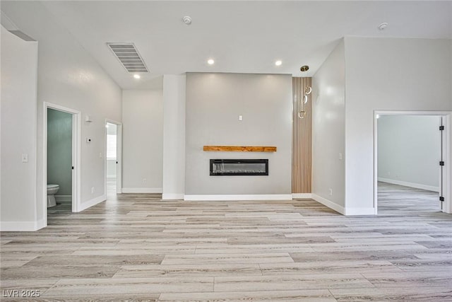 1002 Christopher View Ave, North Las Vegas, NV 89032 - unfurnished living room featuring a glass covered fireplace, light wood-style flooring, and recessed lighting