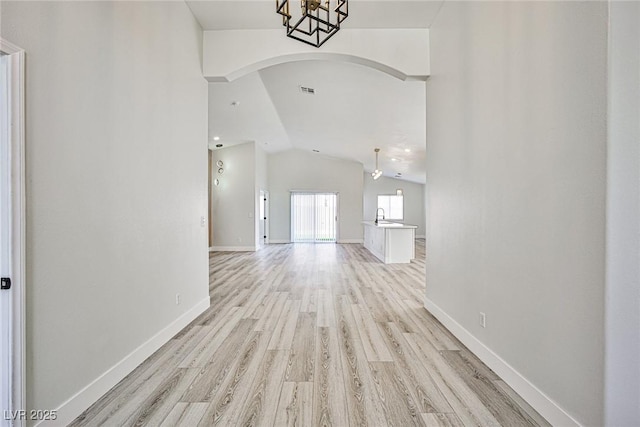 1002 Christopher View Ave, North Las Vegas, NV 89032 - unfurnished living room with arched walkways, vaulted ceiling, and light wood finished floors
