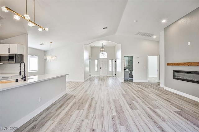 1002 Christopher View Ave, North Las Vegas, NV 89032 - unfurnished living room with lofted ceiling, a chandelier, healthy amount of natural light, and arched walkways