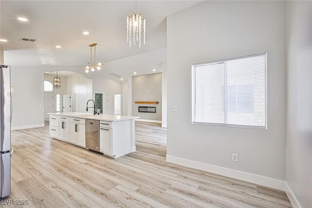 1002 Christopher View Ave, North Las Vegas, NV 89032 - kitchen with stainless steel appliances, a chandelier, white cabinets, hanging light fixtures, and light wood-type flooring