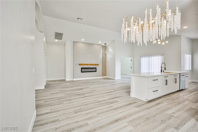 1002 Christopher View Ave, North Las Vegas, NV 89032 - kitchen with a chandelier, light wood-style flooring, white cabinetry, open floor plan, and stainless steel dishwasher