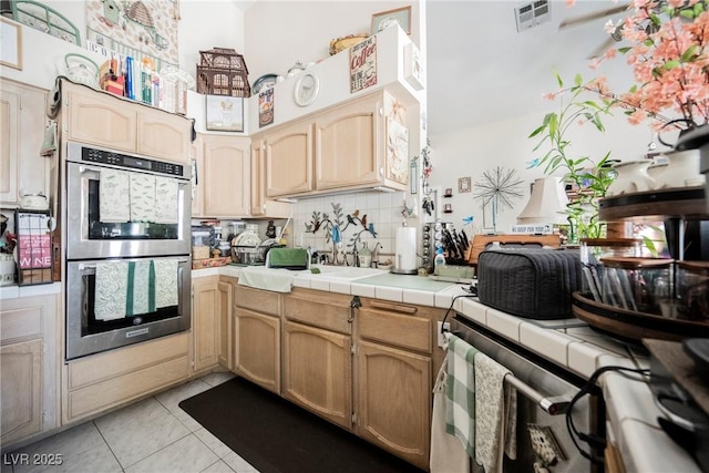 3648 Glen Ridge Way, Las Vegas, NV 89108 - kitchen featuring double oven, light tile patterned floors, tasteful backsplash, tile countertops, and a high ceiling