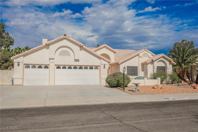 3648 Glen Ridge Way, Las Vegas, NV 89108 - mediterranean / spanish house with an attached garage, driveway, stucco siding, a tiled roof, and a chimney