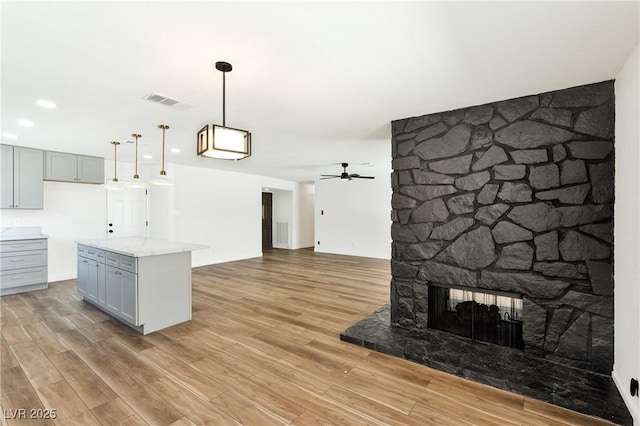 4135 E Harmon Ave, Las Vegas, NV 89121 - kitchen featuring gray cabinets, light wood finished floors, a ceiling fan, hanging light fixtures, and open floor plan