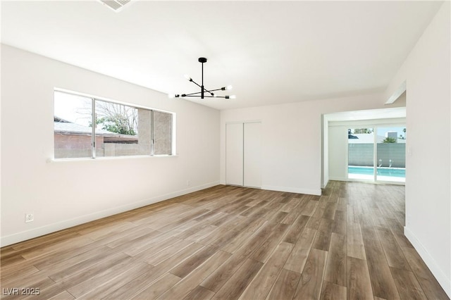 4135 E Harmon Ave, Las Vegas, NV 89121 - empty room featuring healthy amount of natural light, wood finished floors, and a chandelier
