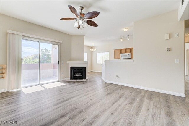 1050 E Cactus Ave Unit 2110, Las Vegas, NV 89183 - unfurnished living room featuring ceiling fan, light wood-type flooring, a fireplace with flush hearth, a chandelier, and rail lighting