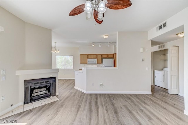 1050 E Cactus Ave Unit 2110, Las Vegas, NV 89183 - unfurnished living room with a ceiling fan, washing machine and clothes dryer, light wood finished floors, a chandelier, and a fireplace with flush hearth