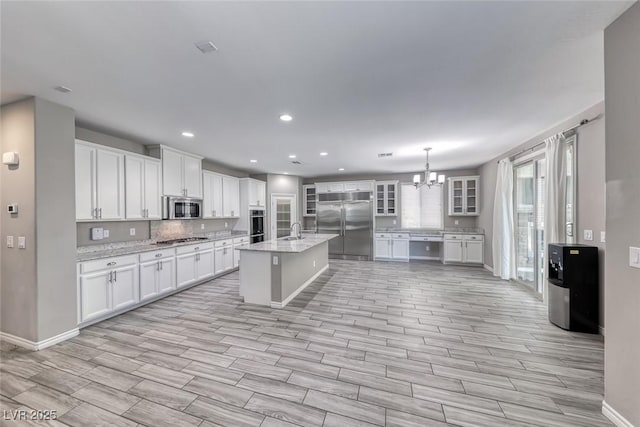 12313 Old Muirfield St, Las Vegas, NV 89141 - kitchen with appliances with stainless steel finishes, light wood-style floors, a chandelier, white cabinets, and recessed lighting