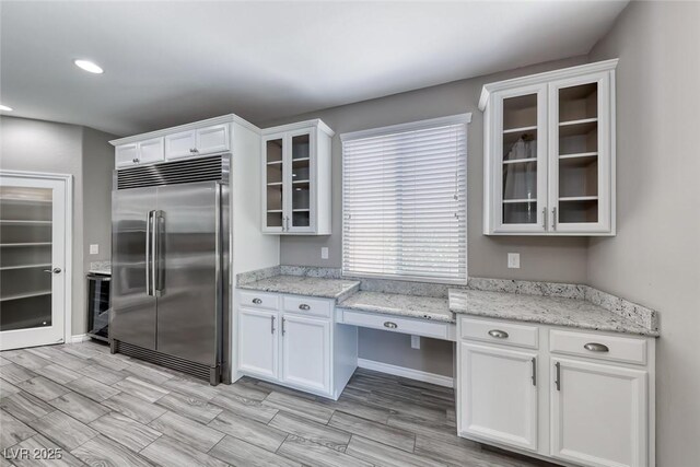 12313 Old Muirfield St, Las Vegas, NV 89141 - kitchen featuring built in refrigerator, white cabinets, glass insert cabinets, wood tiled floors, and recessed lighting