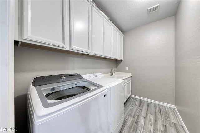 12313 Old Muirfield St, Las Vegas, NV 89141 - washroom featuring independent washer and dryer, light wood-style floors, and cabinet space