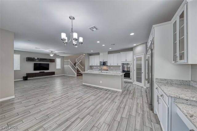 12313 Old Muirfield St, Las Vegas, NV 89141 - kitchen featuring appliances with stainless steel finishes, open floor plan, a ceiling fan, a chandelier, and white cabinets