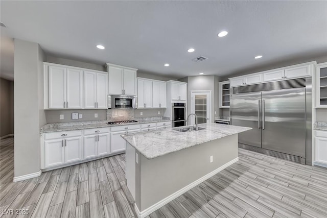 12313 Old Muirfield St, Las Vegas, NV 89141 - kitchen featuring appliances with stainless steel finishes, wood tiled floors, white cabinets, recessed lighting, and a center island with sink