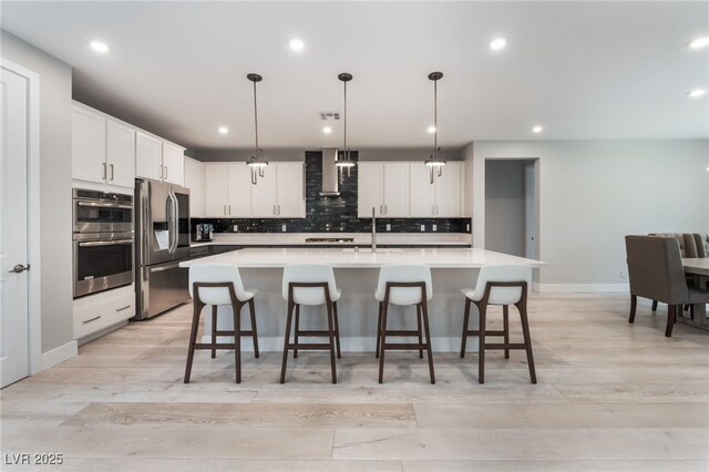10280 Midnight Meteor Ave, Las Vegas, NV 89166 - kitchen with stainless steel appliances, tasteful backsplash, light countertops, a kitchen breakfast bar, and a kitchen island with sink