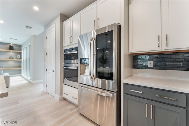 10280 Midnight Meteor Ave, Las Vegas, NV 89166 - kitchen featuring stainless steel appliances, gray cabinets, light wood finished floors, tasteful backsplash, and recessed lighting