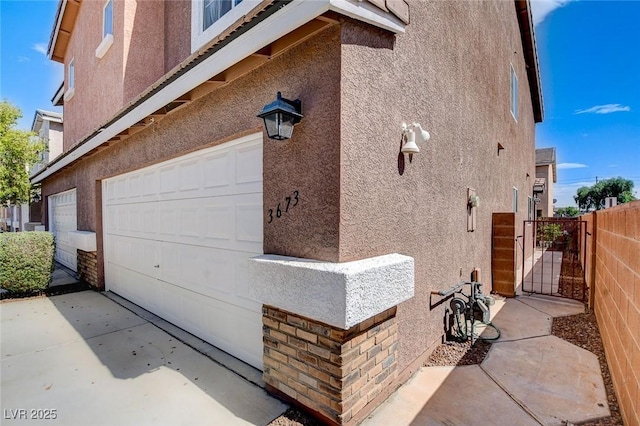 3673 Calypso Beach Ct, Las Vegas, NV 89115 - view of home's exterior featuring stucco siding, a garage, a gate, and driveway