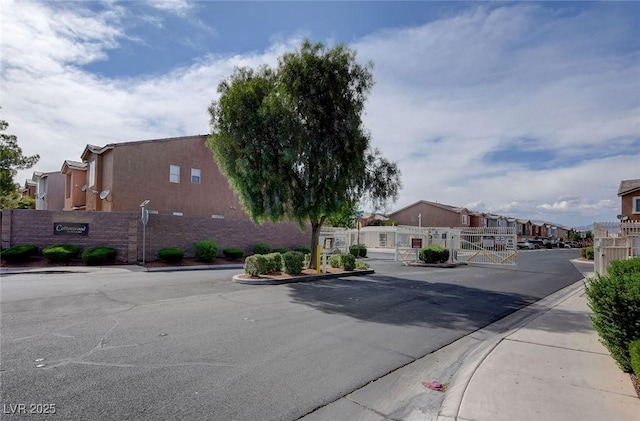 3673 Calypso Beach Ct, Las Vegas, NV 89115 - view of asphalt road featuring a gate, sidewalks, curbs, a residential view, and a gated entry
