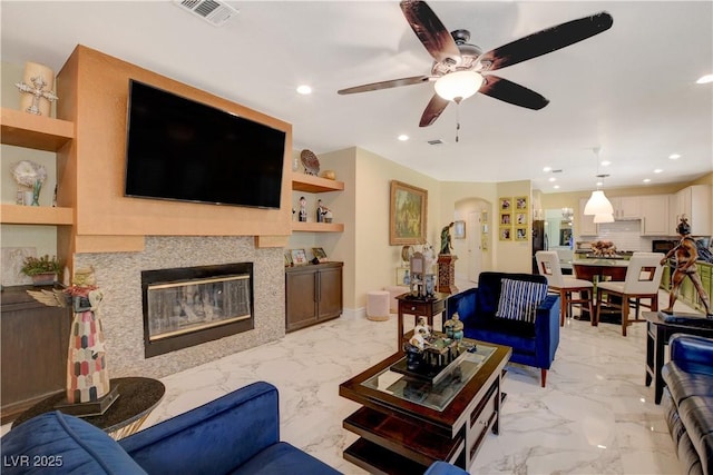 7613 Hackensack Ct, Las Vegas, NV 89128 - living room featuring recessed lighting, ceiling fan, light marble finish flooring, and a glass covered fireplace