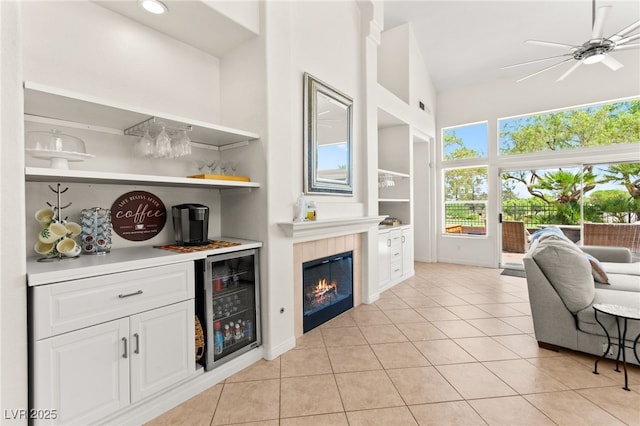 9136 Eagle Ridge Dr, Las Vegas, NV 89134 - indoor dry bar featuring beverage cooler, light tile patterned floors, ceiling fan, a fireplace, and built in features