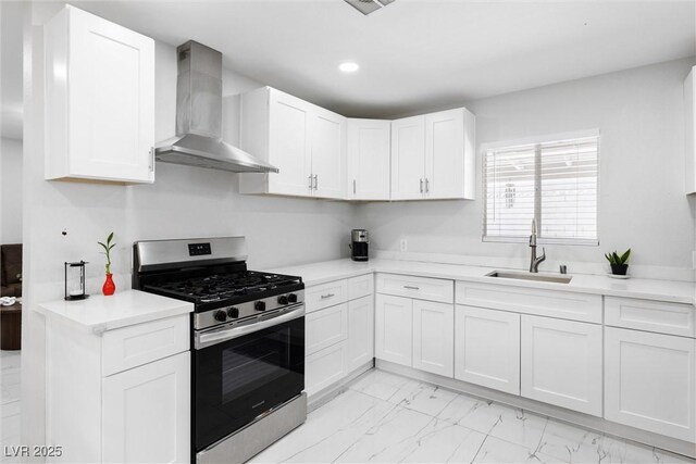 3361 Horizon St, Las Vegas, NV 89121 - kitchen featuring wall chimney exhaust hood, stainless steel gas range oven, light marble finish flooring, white cabinetry, and recessed lighting