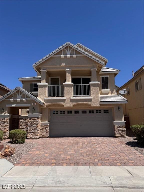 32 Yellow Peak Ave, North Las Vegas, NV 89031 - view of front facade featuring a garage, stone siding, decorative driveway, stucco siding, and a balcony