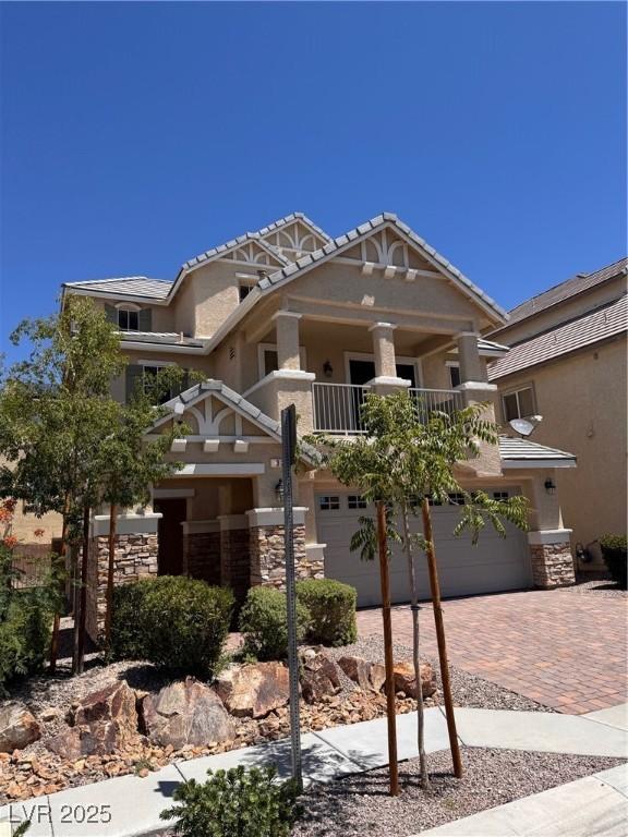 32 Yellow Peak Ave, North Las Vegas, NV 89031 - craftsman inspired home featuring decorative driveway, a garage, a balcony, and stone siding