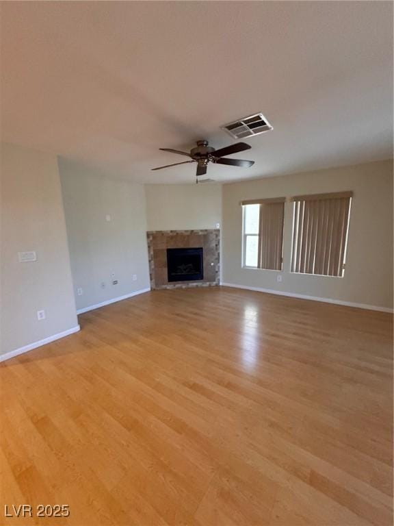 32 Yellow Peak Ave, North Las Vegas, NV 89031 - unfurnished living room with a ceiling fan, light wood finished floors, and a tiled fireplace
