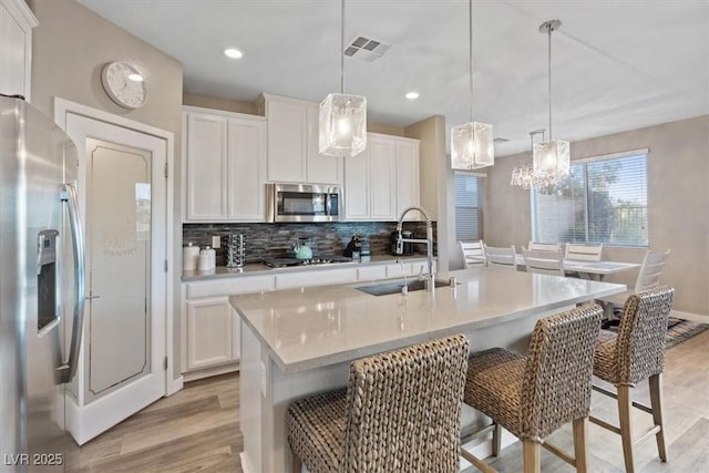 714 Rogue Wave St, Las Vegas, NV 89138 - kitchen with appliances with stainless steel finishes, light wood finished floors, tasteful backsplash, white cabinets, and light countertops