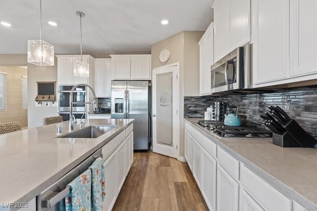 714 Rogue Wave St, Las Vegas, NV 89138 - kitchen with stainless steel appliances, light wood-style flooring, white cabinetry, tasteful backsplash, and pendant lighting