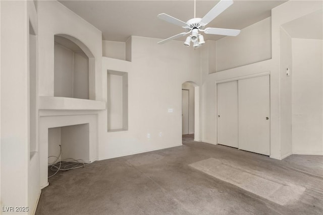 6201 E Lake Mead Blvd Unit 210, Las Vegas, NV 89156 - unfurnished living room with carpet flooring, arched walkways, a ceiling fan, and a towering ceiling