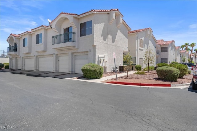 6201 E Lake Mead Blvd Unit 210, Las Vegas, NV 89156 - view of front of property with a garage, a tiled roof, a balcony, a residential view, and stucco siding