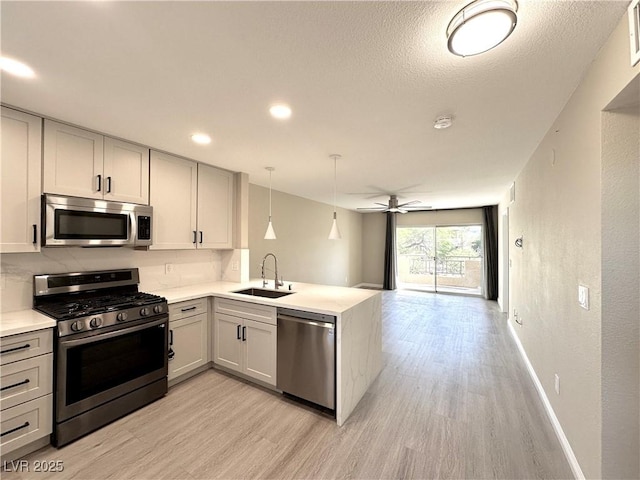 8070 W Russell Rd Unit 2070, Las Vegas, NV 89113 - kitchen with stainless steel appliances, light wood-style flooring, a peninsula, light countertops, and open floor plan