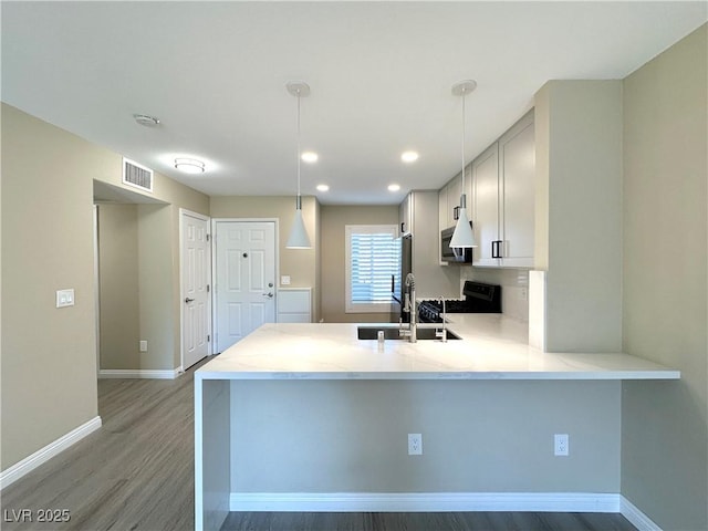 8070 W Russell Rd Unit 2070, Las Vegas, NV 89113 - kitchen featuring light wood-style flooring, a peninsula, stainless steel appliances, hanging light fixtures, and light stone countertops