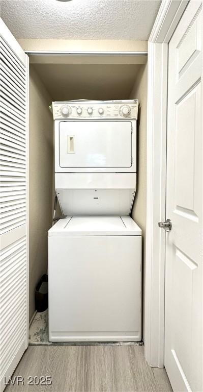 8070 W Russell Rd Unit 2070, Las Vegas, NV 89113 - laundry room with stacked washer and clothes dryer, light wood-type flooring, and a textured ceiling