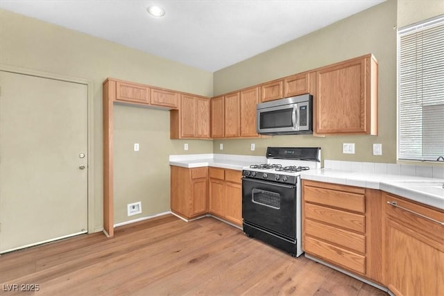 9948 Trailing Vine St, Las Vegas, NV 89183 - kitchen with stainless steel microwave, gas range, light wood finished floors, light countertops, and recessed lighting