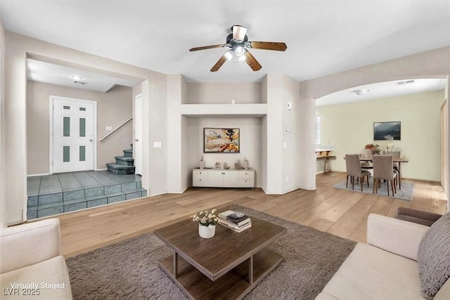 9948 Trailing Vine St, Las Vegas, NV 89183 - living room featuring wood finished floors, arched walkways, a ceiling fan, and stairs