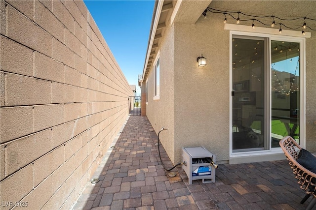 3447 Covilha Ln, Henderson, NV 89044 - view of side of home featuring stucco siding, a patio area, and a gate