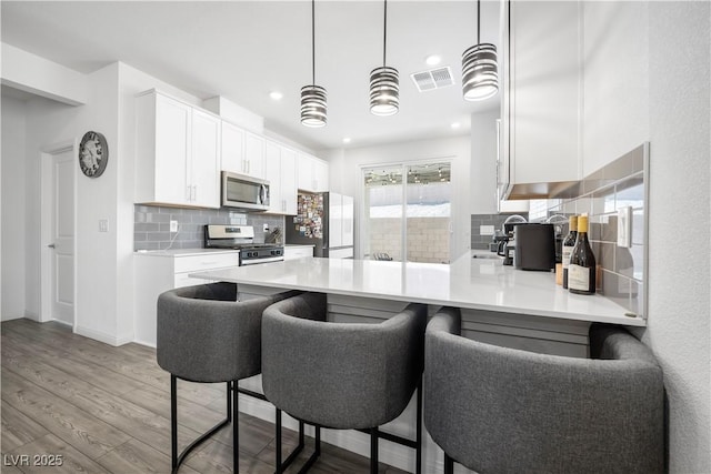 3447 Covilha Ln, Henderson, NV 89044 - kitchen featuring appliances with stainless steel finishes, tasteful backsplash, white cabinetry, light wood-style flooring, and light countertops