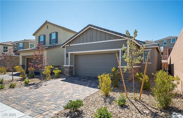 3447 Covilha Ln, Henderson, NV 89044 - view of front of home with stone siding, board and batten siding, driveway, an attached garage, and a tiled roof