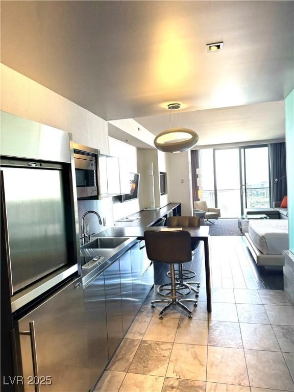 4381 W Flamingo Rd Unit 3708, Las Vegas, NV 89103 - kitchen with stainless steel microwave, open floor plan, and hanging light fixtures